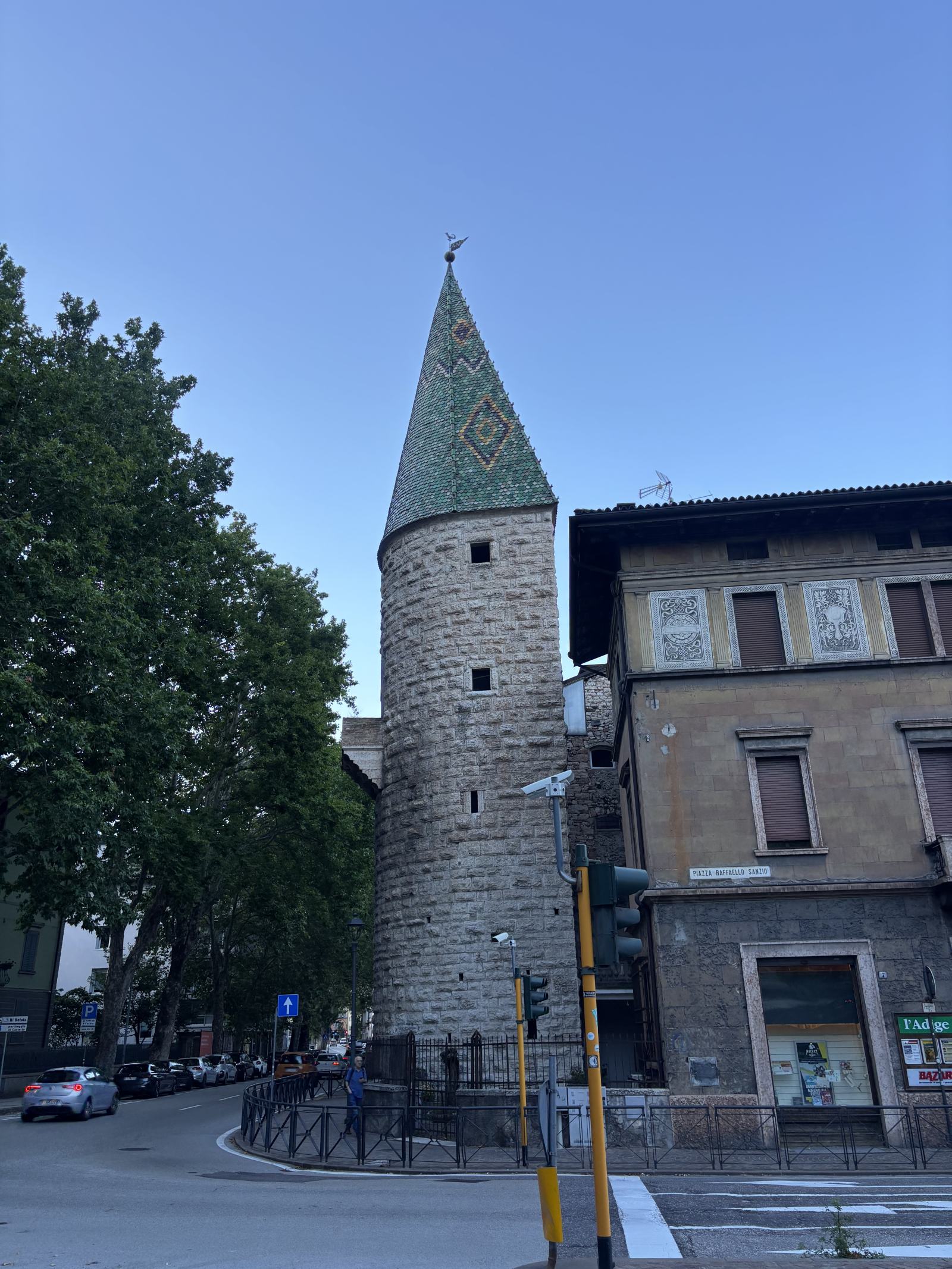 Runder Steinturm mit buntem, spitzem Dach in Trient