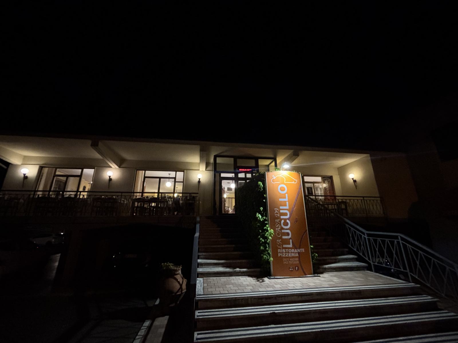 Außenansicht des Restaurants Lucullo bei Nacht, beleuchtete Fassade und Treppe.